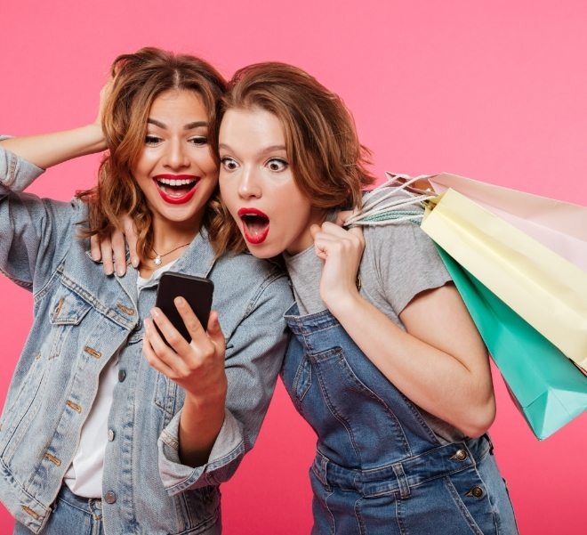 imgi_4_shocked-two-women-friends-holding-shopping-bags-using-mobile-phone